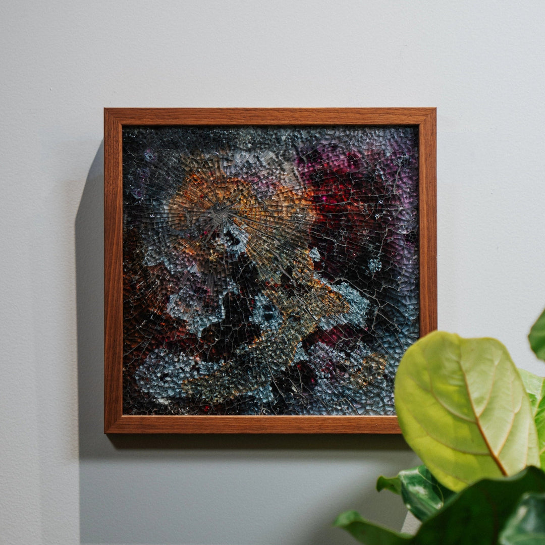 Framed abstract painting on a wall with a plant in the foreground